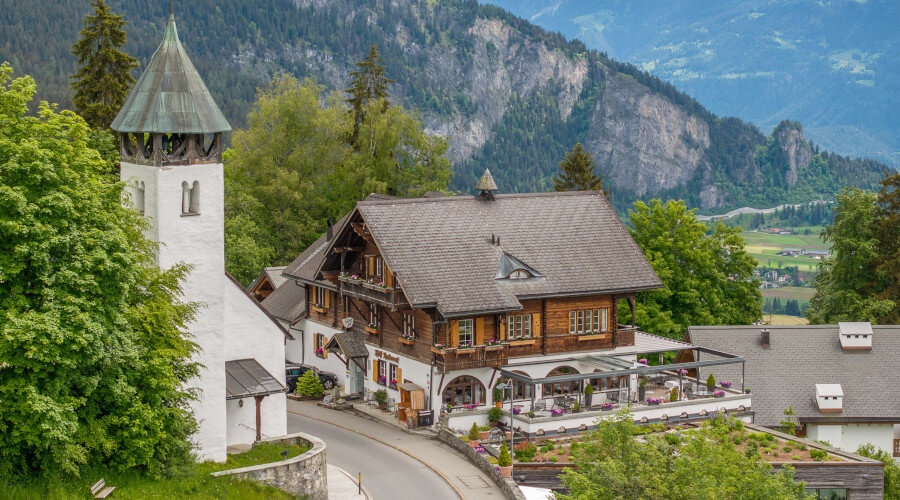 Hotelgebäude im Sommer mit Kappelle in den Bergen