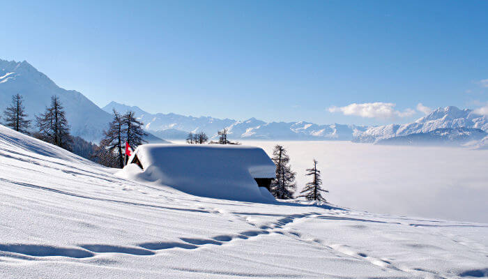 Verschneite Hütte in Ernergalen vor Nebelmeer
