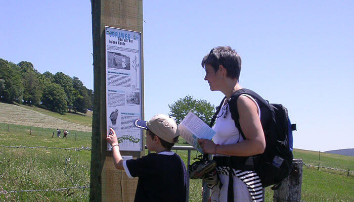 Infotafel mit zwei Personen auf dem Juraweg Thal im Sommer