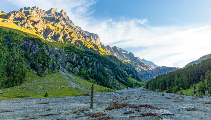 Geröll im Kanderflussbett mit grünen und besonnten Bergketten