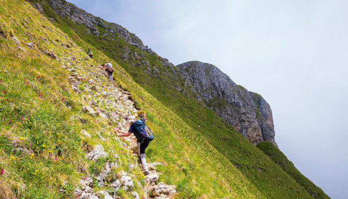 Wanderer die den steilen Berg auf dem Gantrisch hochkraxeln