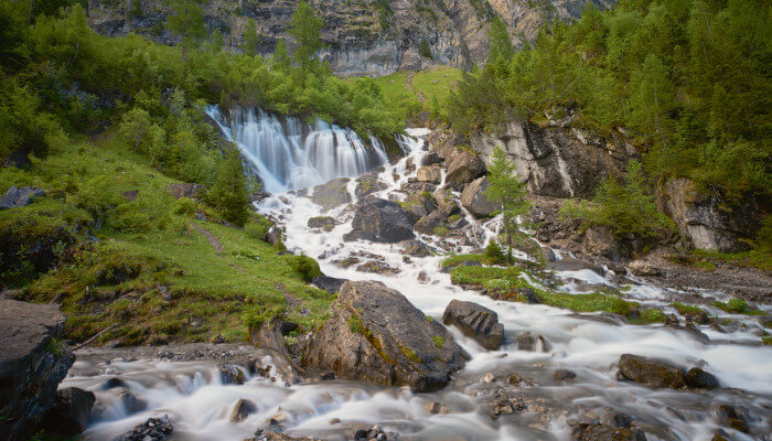 Wasserfall und Fluss welcher vom Berg ins Tal fliesst im Sommer