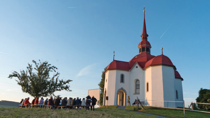 Menschen vor einer Kirche in der Abenddämmerung