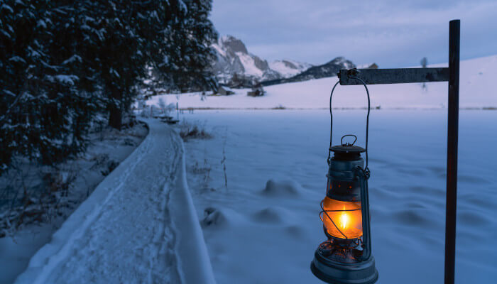 Leuchtende Laterne an einem Weg in der Abenddämmerung im Winter