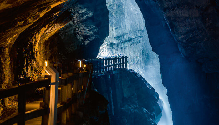 Höhle durch die ein Weg führt und ein Fluss