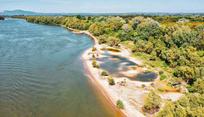 blauer Fluss fliesst vorbei an Bäumen und Sandstränden