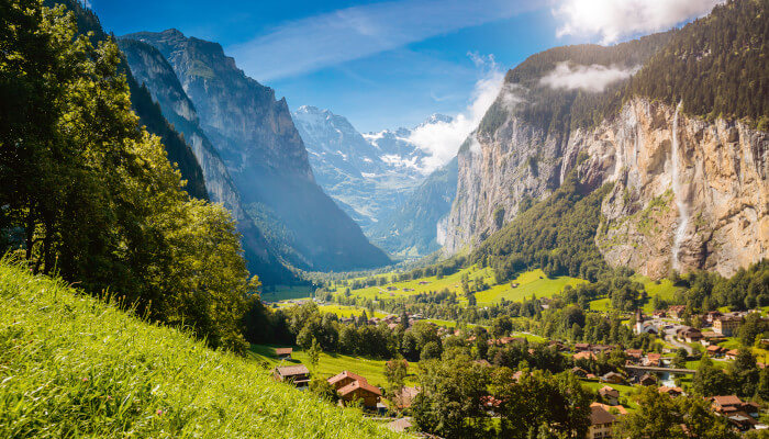 Bergtal im Sommer mit Häusern und Wälder